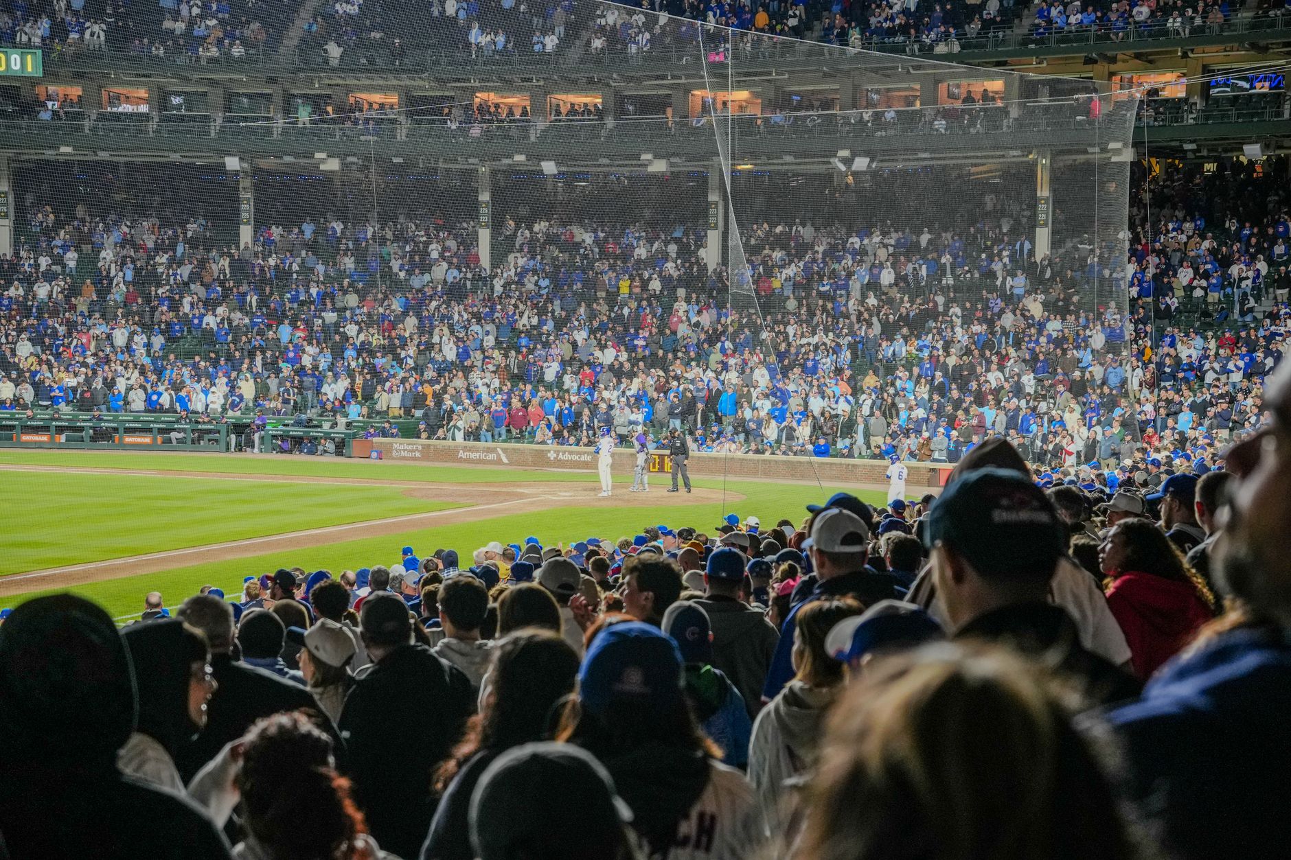 Energetic scene of a nighttime baseball game with a packed stadium crowd.