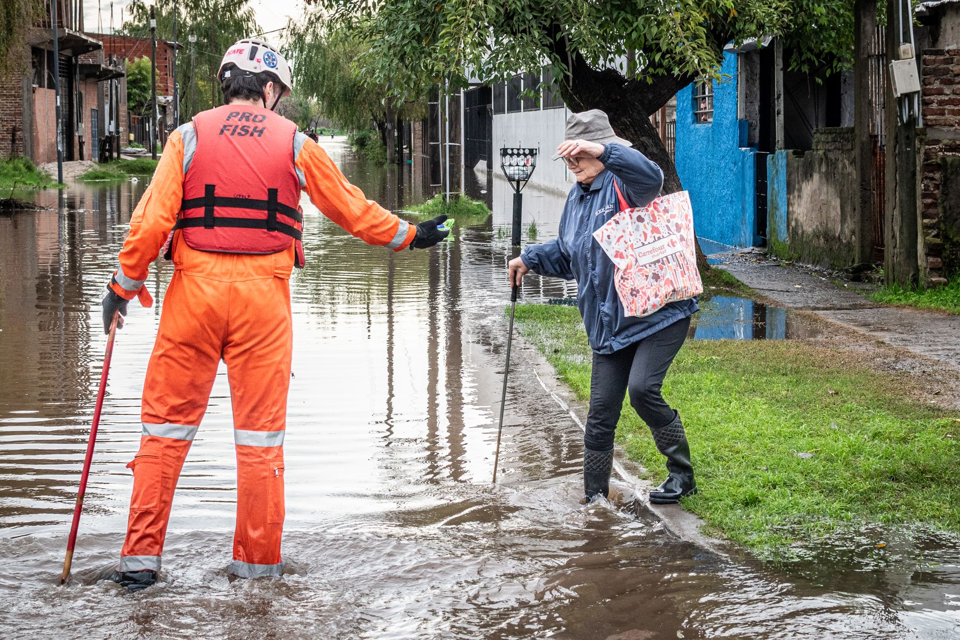A rescue worker assists an elderly woman on a flooded street in Buenos Aires, Argentina.