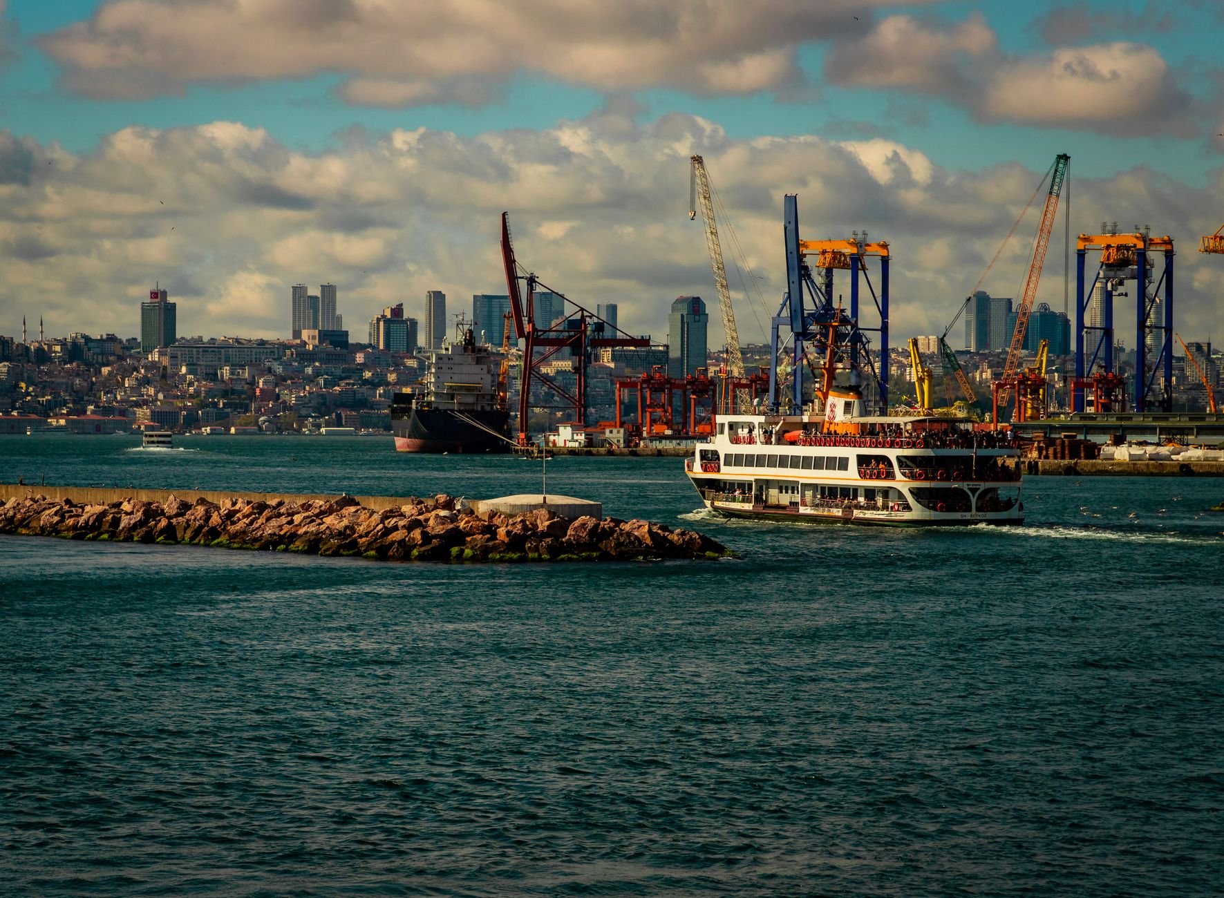 Explore the bustling İstanbul harbor with ferries, cranes, and a stunning city skyline.